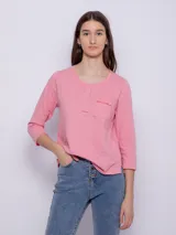 Remera rosa de algodón, de manga 3/4, con cuello redondo abotonado y bolsillo en el pecho con volado.