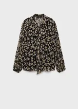 Blusa de gasa con estampado floral de margaritas sobre fondo negro, diseño recto semitransparente con cuello pico y detalle de lazo frontal. Cuenta con mangas largas y forro interior.
