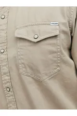 Camisa de denim color beige, con cuello clásico, cierre con botones y dos bolsillos frontales con solapa abotonada. Corte slim.