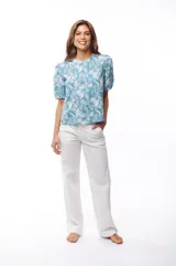 Blusa celeste con estampado de flores blancas, mangas cortas abullonadas y cuello redondo.