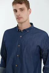 Camisa de jean azul oscuro de manga larga con cuello abotonado y bolsillo en el pecho.