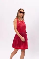 Vestido corto de tejido de punto a rayas verticales en tonos rosa y rojo. Incluye cinturón tejido con flecos.