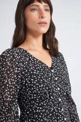 Blusa rosa con estampado de flores blancas y amarillas, cuello en V, manga larga abullonada y cierre frontal con botones.