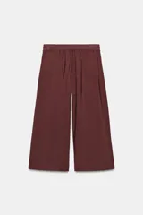 Pantalón tipo culotte de tiro medio, con pierna ancha, bolsillos delanteros y detalle de pinzas. Cuenta con cierre frontal de cremallera y gancho metálico.