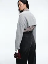 Sweater de punto en color gris, con diseño crop de mangas largas y cuello bote. Presenta una textura acanalada y un corte moderno que permite superposiciones.