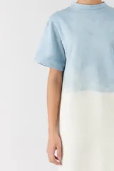 Vestido midi de corte recto, con diseño bicolor en degrade que combina celeste en la parte superior y blanco marfil en la inferior. Posee mangas cortas y cuello redondo.