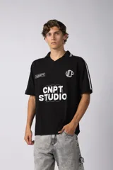 Remera tipo chomba tejida de algodón color negro, con cuello en V y mangas cortas. Presenta detalles de rayas blancas en cuello y mangas, y estampados con logos en el frente.