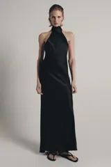 Vestido largo de satén negro con cuello halter subido y espalda descubierta. Presenta un diseño fluido con bajo en línea evasé.