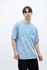 Remera celeste con efecto marmolado, bolsillo en el pecho con parche decorativo y arte en la espalda baja. De calce oversize y algodón lavado con textura extra suave.