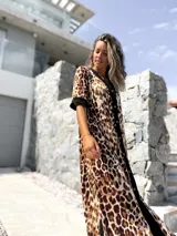Vestido midi con estampado animal print de leopardo en tonos beige y marrón, con cierre frontal de botones y detalles en color negro en el cuello, mangas y borde central.