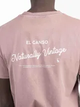 Camiseta celeste de manga corta con cuello redondo y estampado en la espalda con el logo de la marca y la frase "Naturally Vintage".