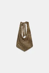 Top halter de cuello fluido y bajo asimétrico, con estampado animal print tipo leopardo y cierre de lazos en la espalda.