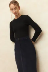 Maxifalda de pana de tiro alto, con cierre frontal, botón metálico, cuatro bolsillos y abertura trasera.