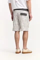 Short de baño estilo surf color gris, de largo medio, con estampado geométrico abstracto y cordón ajustable en la cintura. Incluye bolsillo trasero con solapa.