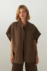 Chaleco marrón de lana con cuello mao, solapas pronunciadas, bolsillos ojal y terminaciones envivadas.