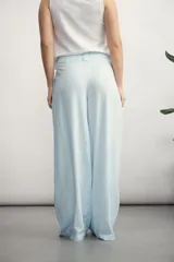 Pantalón de corte sastrero y tiro alto, color celeste, con pinzas frontales y diseño de pierna ancha.