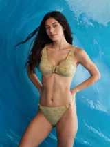 Conjunto de bikini color pistacho con estampado de hojas. El corpiño es de corte triangular con detalle de aro metálico en el centro. La bombacha es de corte clásico con aros metálicos en los laterales.