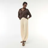 Pantalón de punto arrugado color beige, de tiro alto y corte amplio con botamanga ajustada.