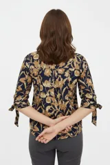 Blusa estampada de viscosa con diseño abstracto en tonos beige, negro y marrón, escote en V con cuello mao y mangas tres cuartos con detalles de lazos en los puños.