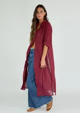Camisa larga tipo vestido, de corte recto y diseño traslúcido, con cuello clásico, cierre frontal de botones y mangas cortas con dobladillo.