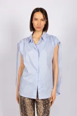 Camisa celeste sin mangas con cuello clásico y cierre frontal con botones. Presenta tiras regulables en los hombros.