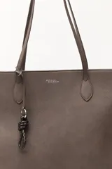 Cartera tipo tote de diseño minimalista y estructura flexible, confeccionada en material sintético con acabado mate. Cuenta con asas largas para llevar al hombro y un compartimento principal amplio.