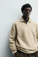 Sudadera de corte relajado confeccionada en tejido con textura, color beige. Presenta cuello solapa con cierre frontal de cremallera, manga larga y acabados con cinta elástica en puños y ruedo.