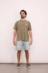 Remera verde militar de corte oversize con cuello redondo y estampado en la espalda con el logo de Brixton, una flor de hibisco y la frase "Where hibiscus grows, peace flows".