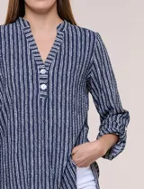 Blusa holgada de color verde con diseño de rayas verticales blancas, escote en V con cuello mao y pechera corta con botones. Mangas tres cuartos regulables y bajo redondeado.