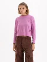 Sweater de tejido de punto en color gris, con cuello redondo, mangas largas y detalle de bordado amarillo en el puño y en el lateral inferior. Presenta un corte recto y estructura ligera.