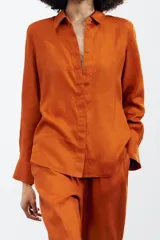 Camisa color coral confeccionada en lino 100%, de corte recto, con cuello solapa, manga larga con puños abotonados y cierre frontal con botones.