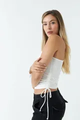 Top asimétrico de una sola manga larga, color azul, con jaretas ajustables en ambos laterales del torso que permiten regular el largo de la prenda.