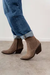 Bota corta de cuero vacuno color negro, con puntera metálica plateada, caña baja, cierre lateral y taco de 7cm. Fabricada en Uruguay.