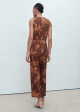 Mono largo marrón con estampado de palmeras, diseño sin mangas, cuello redondo, detalles cut-out en los laterales y un nudo decorativo en la parte delantera.