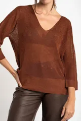 Sweater de punto con acabado brillante, cuello en V y mangas tres cuartos. Presenta un diseño holgado y tejido traslúcido.