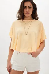 Remera corta de corte relajado y silueta holgada, color amarillo claro con acabado jaspeado y detalles de bordes deshilachados.