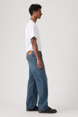 Jeans de corte holgado y tiro medio, con diseño clásico de cinco bolsillos y cierre de botones. Presentan un lavado azul medio con efecto desgastado en los muslos.