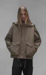 Campera técnica liviana color beige, confeccionada en microfibra de alta densidad con acabado mate. Presenta mangas desmontables que permiten convertirla en chaleco, cuello tipo camisa, cierre frontal oculto bajo cartera y logo bordado en el pecho. Incluye cuatro bolsillos frontales de gran tamaño con solapa y puños con elástico.