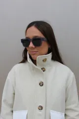 Campera de paño de lana en color beige jaspeado, con diseño oversize. Presenta detalles en pana color marrón chocolate en los puños y en las tapas de los bolsillos frontales. Cuenta con cierre frontal de botones grandes y cuello alto.