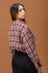 Camisa de corte relajado con estampado de cuadros en tonos bordó, blanco y negro. Presenta cuello camisero, cierre frontal con botones y mangas largas con puños abotonados.