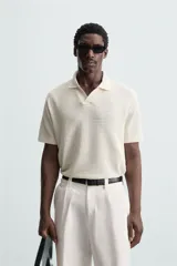 Polo negro de manga corta con cuello solapa y abertura frontal. Presenta un tejido jacquard con textura geométrica sutil.