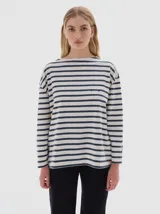 Remera de manga larga con calce holgado, confeccionada en algodón. Presenta un diseño a rayas horizontales en tonos beige y negro, con bordado de letras SP en el pecho y estampa de la marca en la manga.