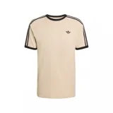 Remera de algodón color beige con cuello redondo y bordes de mangas en color negro. Presenta las icónicas tres rayas de la marca en color negro sobre los hombros y mangas, junto con el logo del trébol bordado en el pecho.