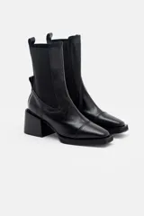 Bota tipo chelsea de cuero color bordó, con paneles elásticos laterales negros, puntera cuadrada y taco bloque negro.