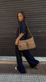 Bandolera de tafeta impermeable color beige, con dos bolsillos frontales con cierre y correa regulable. Diseño práctico y liviano ideal para uso diario.