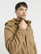 Campera de abrigo estilo parka, color verde oscuro, con capucha desmontable, cierre frontal con botones y cremallera, múltiples bolsillos frontales y en la manga.