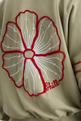 Campera oversize color crudo de algodón con spandex, corte de largo intermedio, mangas largas con detalles de costuras en zigzag bordadas y un gran diseño bordado a mano de una flor en la espalda.