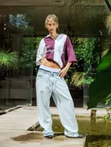 Chomba de piqué con diseño color block vertical en negro y verde oscuro, cuello polo y cierre frontal parcial. Presenta inscripciones en el frente.