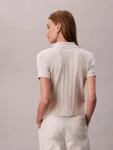 Chomba Calvin Klein de manga corta en color blanco, con cuello clásico, cierre frontal con botones y diseño de jacquard con estampado integral.