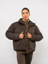 Campera puffer corta Umbro, color marrón, con cuello alto, cierre frontal y logo bordado en el pecho.